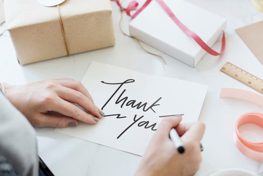 A woman writing a thank you card for a gift she received 