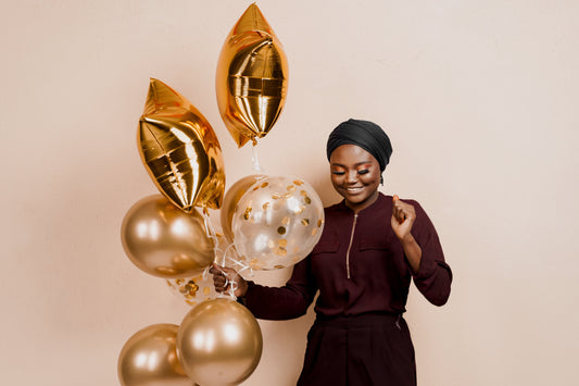 Young Black woman celebrating her golden birthday with balloons 