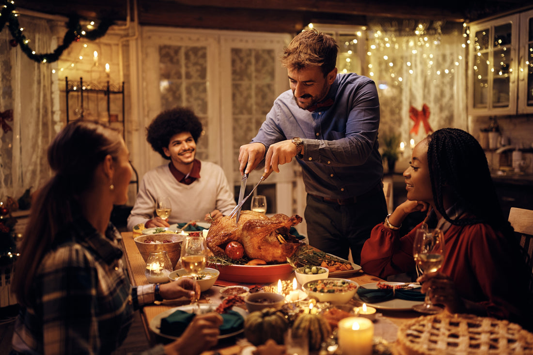 Man carving a turkey among group of friends celebrating Friendsgiving 