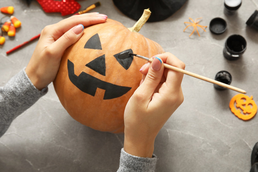 Woman decorating a pumpkin by painting it 