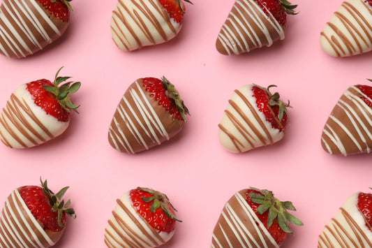 Chocolate-covered strawberries with chocolate drizzle on a pink background 