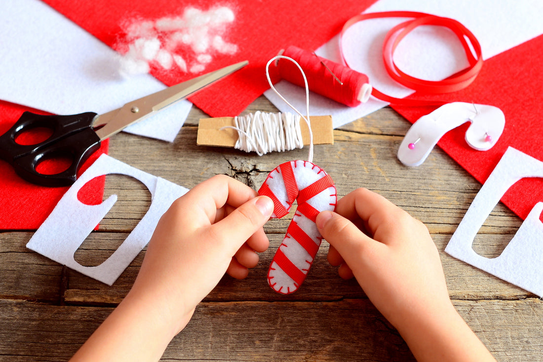 Child making DIY christmas ornaments to create candy cane felt ornaments