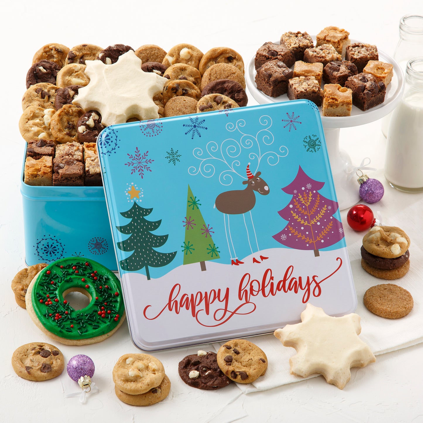 Blue Happy Holidays tin with an assortment of Nibbler bite sized cookies, brownie bites, frosted snowflake cookies and a frosted wreath cookie 