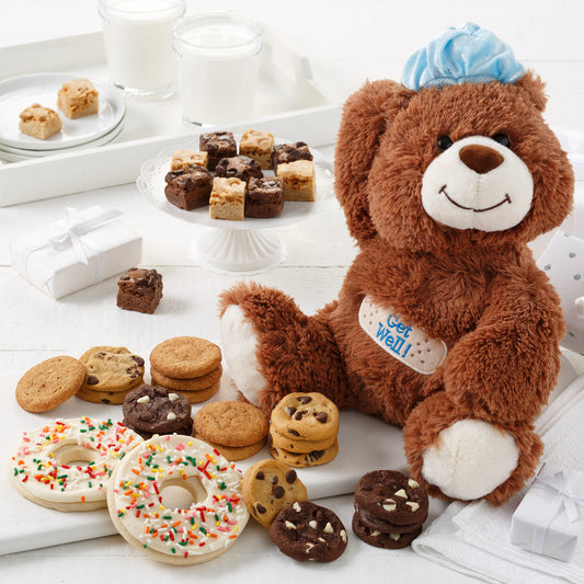 A stuffed Get Well bear surrounded by an assortment of nibblers, brownie bites, and frosted donut cookies with sprinkles