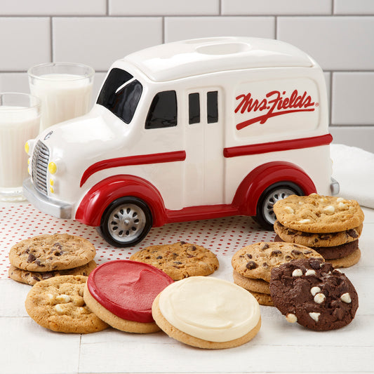 A Mrs Fields old fashioned milk truck cookie jar surrounded by an assortment of original cookies and two frosted cookies