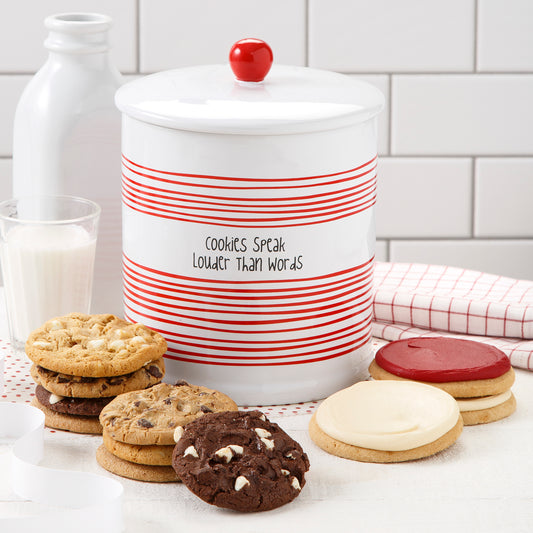 A cookie jar with the sentiment of Cookies Speak Louder Than Words and surrounded by an assortment of original cookies and three frosted round cookeis