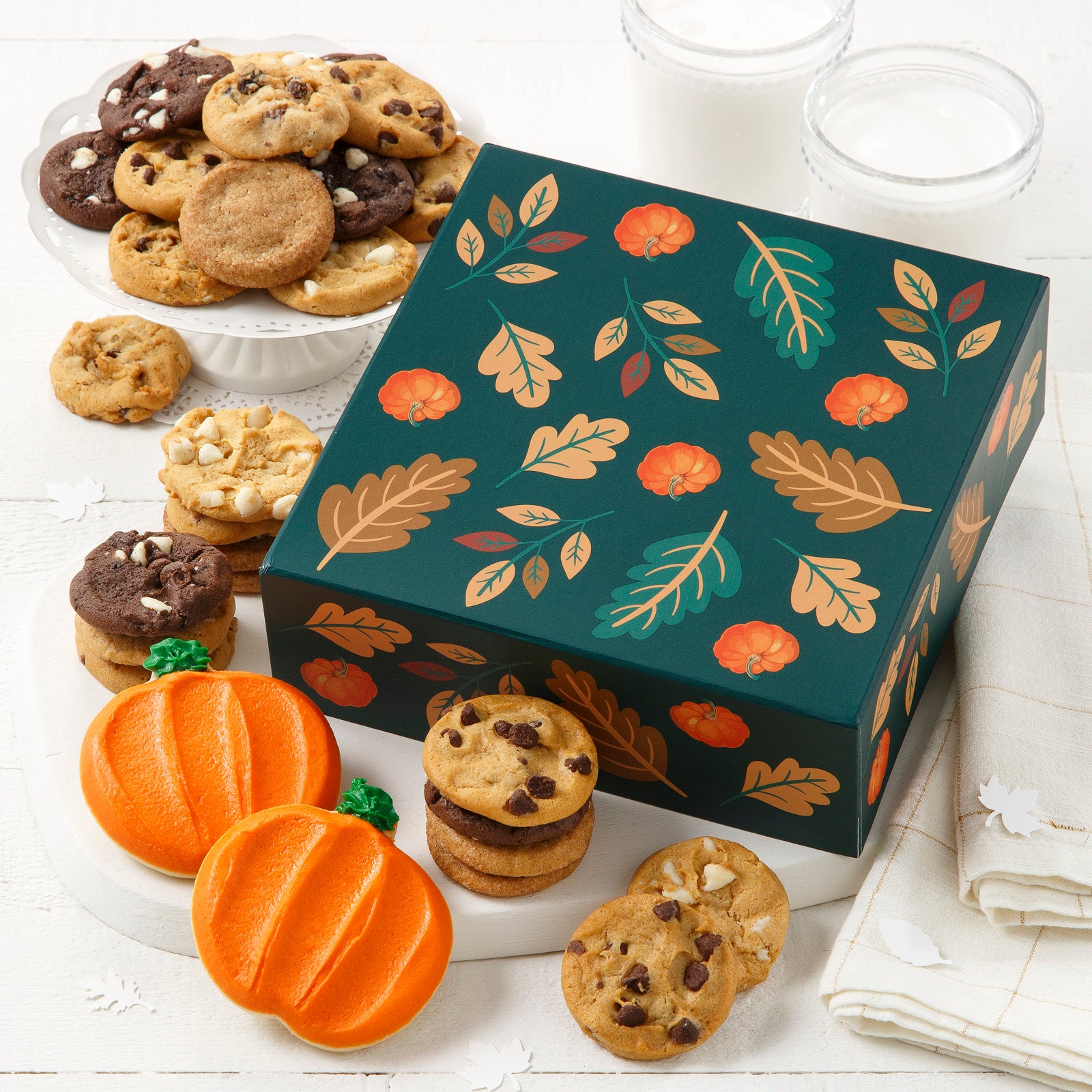 Dark green fall themed box with an variety of leaves and pumpkins, This box is filled with an assortment of Nibblers® and frosted pumpkin cookies