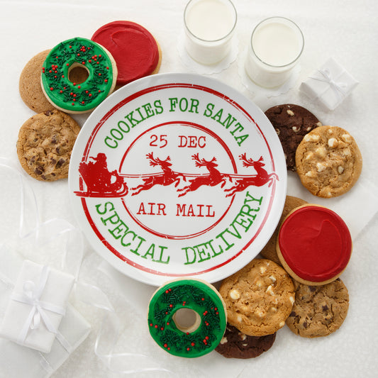 A red and green Christmas plate that says Cookies for Santa Special Delivery and 25 Dec Air Mail and is surrounded with an assortment of original cookies, two frosted wreath cookies with sprinkles, and two frosted red cookies.