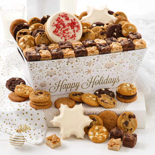 A Happy Holidays crate decorated with a gold and white holiday pattern and filled with an assortment of Nibblers®, brownie bites, two frosted snowflake cookies and one peppermint sprinkle cookie.