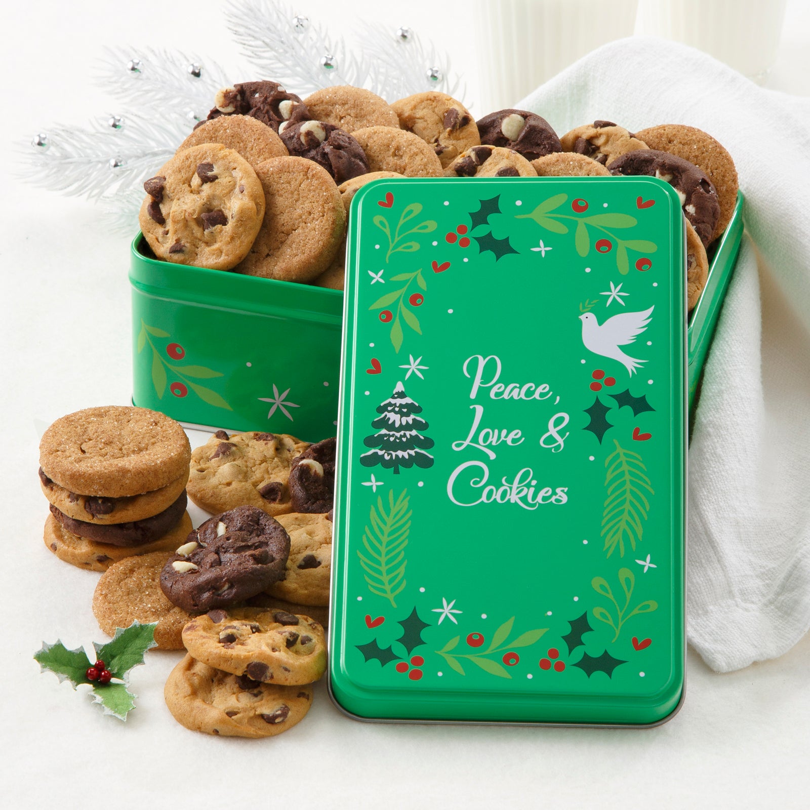 A green Peace, Love, & Cookies tin decorated with a holiday wreath and filled with an assortment of Nibblers®