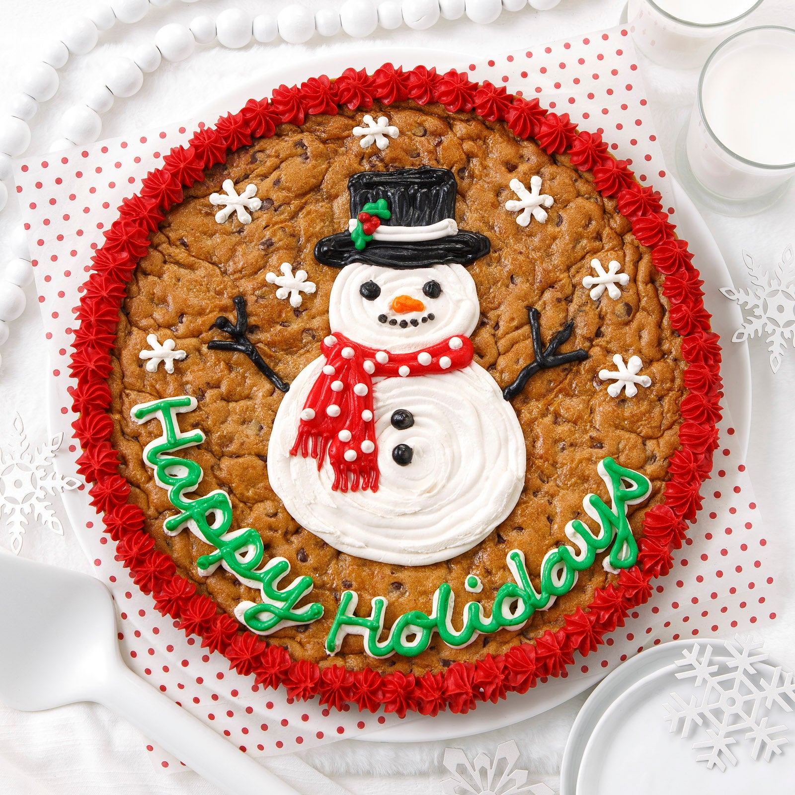 A Happy Holidays s cookie cake decorated with a snowperson surrounded buy falling snowflakes 