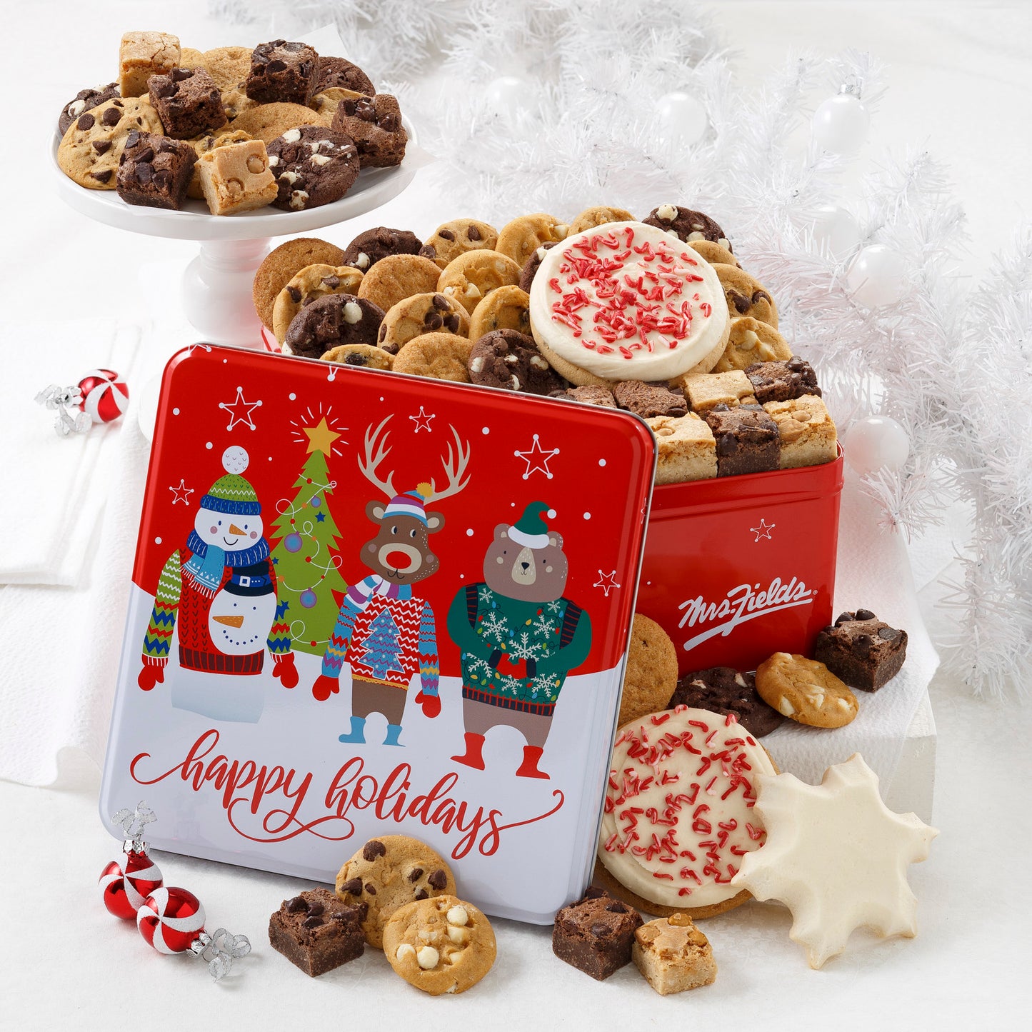 Red Happy Holidays tin featuring colorful carolers decked out in their holiday best. Includes 36 Nibblers® bite-sized cookies, 18 brownie bites, 1 frosted snowflake cookie and 2 frosted peppermint round cookies.