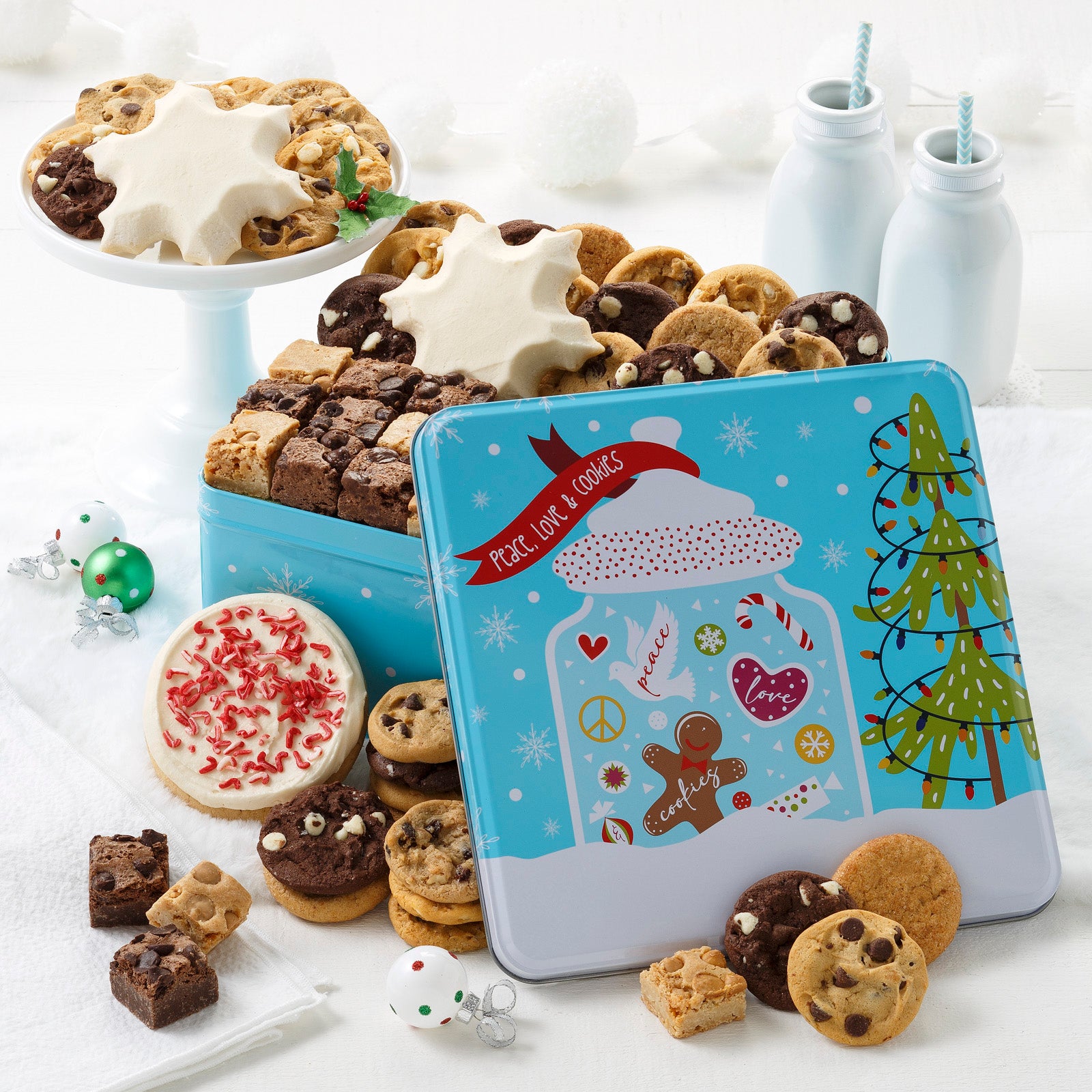 Blue Peace, Love, & Cookies tin decorated with a holiday jar of festive sweets. The tin is filled with an assortment of Nibblers®, brownie bites, one frosted peppermint round cookies with sprinkles and two frosted snowflake cookies