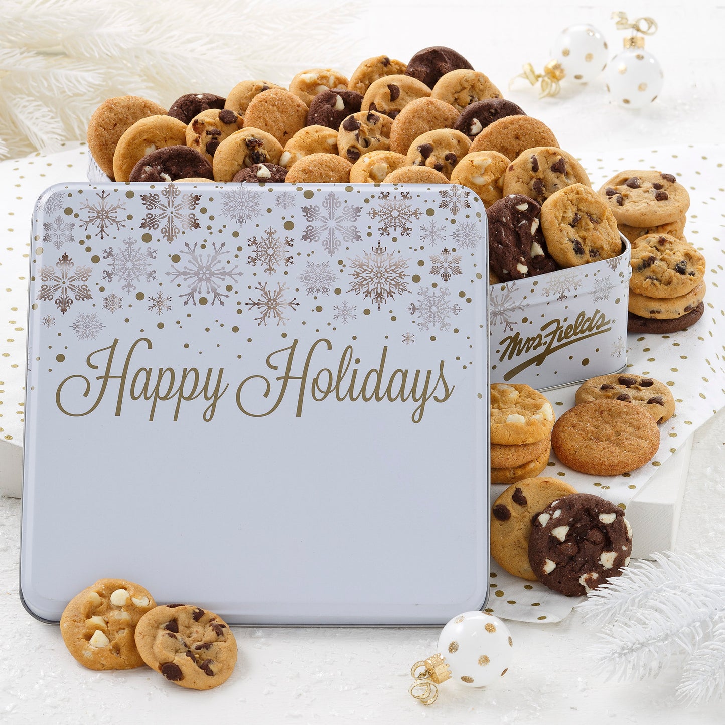 A Happy Holidays white tin decorated with gold and silver snowflakes and filled with Nibblers®