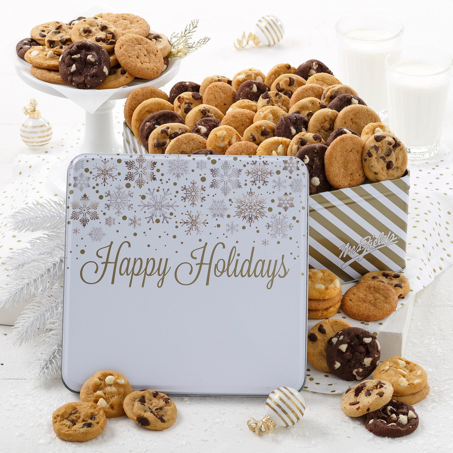 A happy holidays white tin decorated with silver and gold snowflakes filled with an assortment of Nibblers®