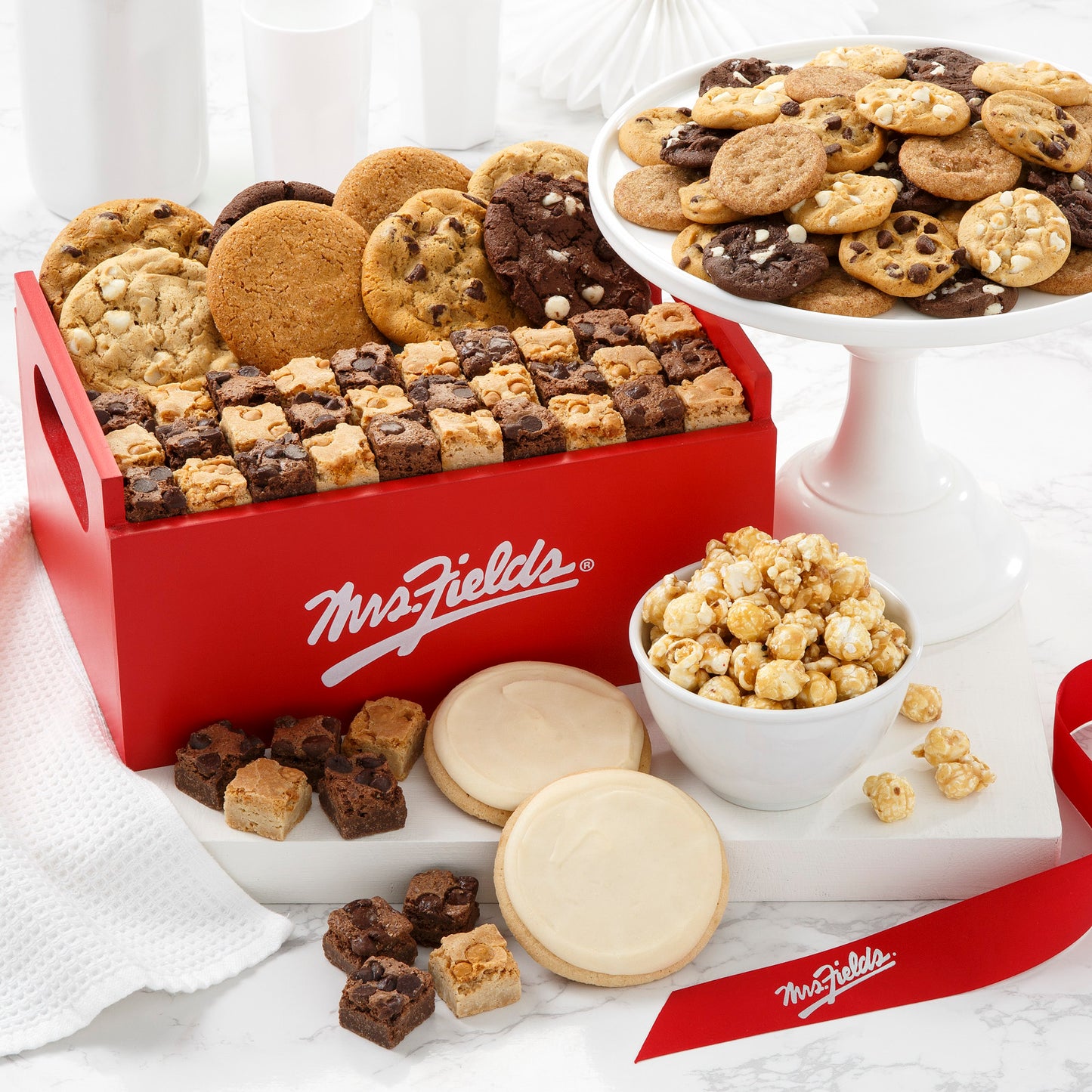 an assortment of 48 Nibblers® bite-sized cookies, 36 brownie bites, 8 original cookies, 2 frosted cookies, and 4 ounces of toffee nut popcorn.