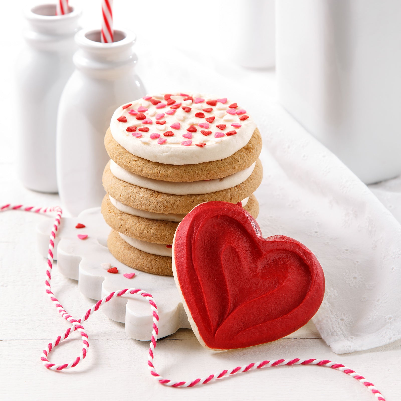 Frosted round cookies with heart sprinkles and a frosted red heart cookie